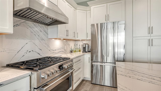 kitchen with light wood-type flooring, backsplash, stainless steel appliances, extractor fan, and white cabinets