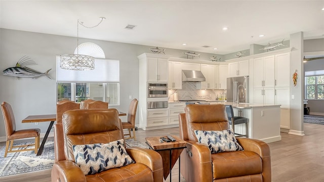 kitchen featuring white cabinets, appliances with stainless steel finishes, hanging light fixtures, and range hood