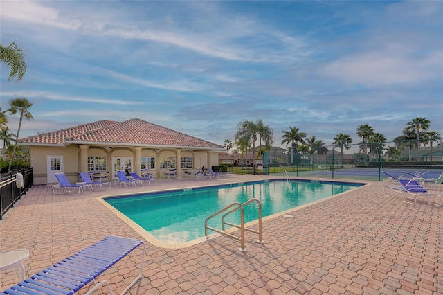 view of swimming pool featuring tennis court and a patio area