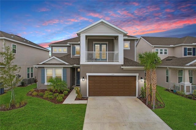 view of front of home with a yard, central air condition unit, a balcony, and a garage