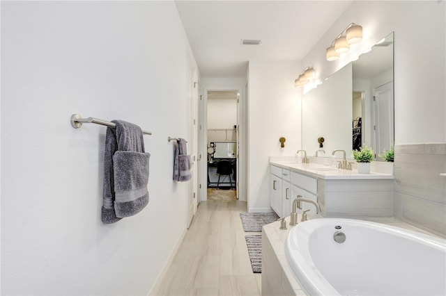 bathroom with vanity and tiled tub