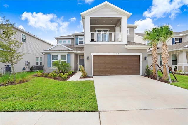 view of front of property featuring a garage, a balcony, a front yard, and central AC