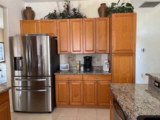 kitchen featuring stone counters, appliances with stainless steel finishes, and light tile patterned floors