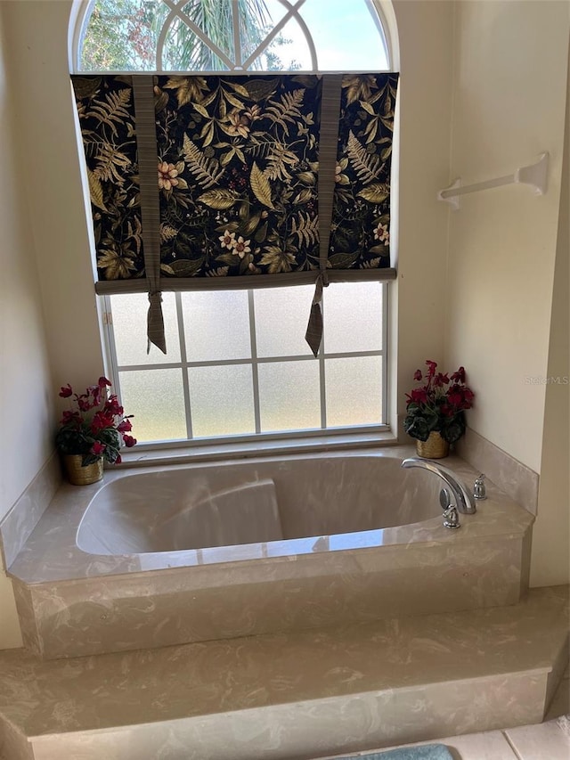 bathroom with tile patterned floors, plenty of natural light, and a relaxing tiled tub