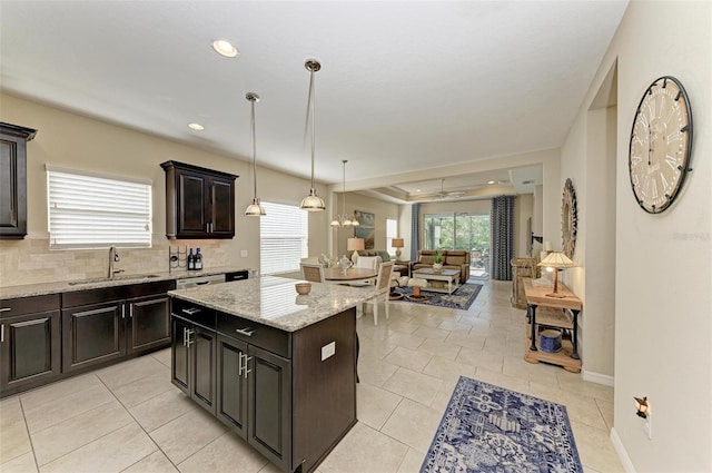 1387 Still River Dr, Venice, FL 34293 - kitchen featuring a center island, ceiling fan, open floor plan, light stone counters, and pendant lighting