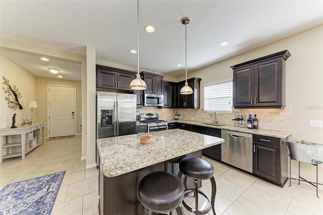 kitchen with dark brown cabinetry, a center island, hanging light fixtures, backsplash, and appliances with stainless steel finishes