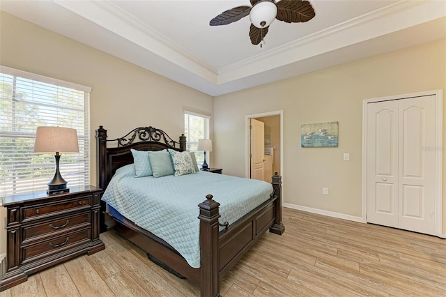 bedroom featuring ensuite bath, ceiling fan, light wood-type flooring, a closet, and ornamental molding