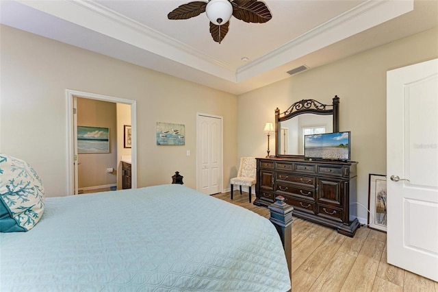 bedroom featuring ensuite bathroom, ceiling fan, a tray ceiling, and light hardwood / wood-style flooring