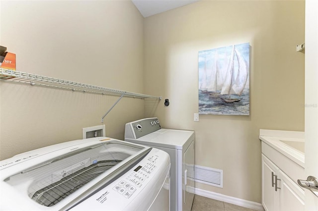 laundry area featuring cabinets, light tile patterned floors, and washing machine and clothes dryer