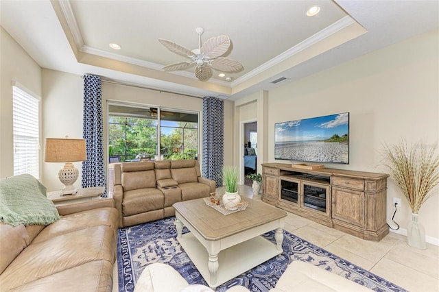 tiled living room featuring a tray ceiling, ceiling fan, and crown molding