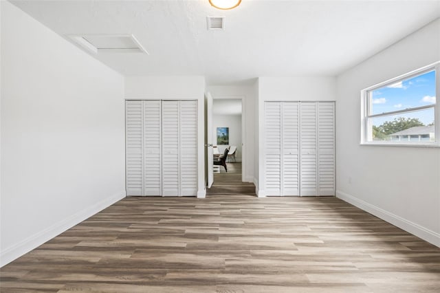 unfurnished bedroom featuring multiple closets and hardwood / wood-style floors