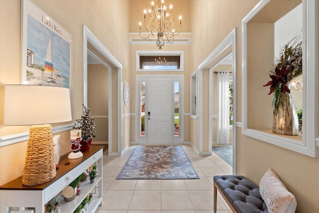 entryway with an inviting chandelier, a towering ceiling, and light tile patterned flooring