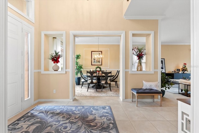 foyer entrance with crown molding, a healthy amount of sunlight, a chandelier, and light tile patterned floors