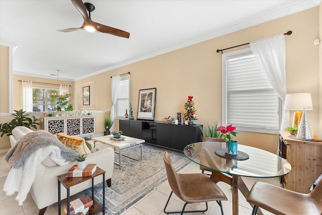 tiled living room with ceiling fan with notable chandelier and ornamental molding