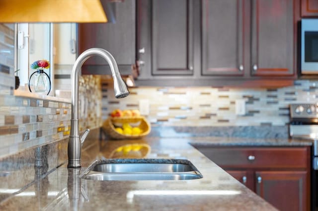 kitchen featuring stainless steel range with electric stovetop, backsplash, and sink