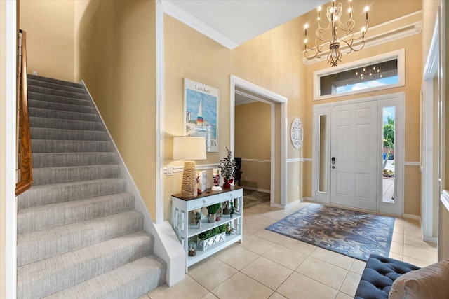 tiled foyer entrance with crown molding, a chandelier, and a towering ceiling