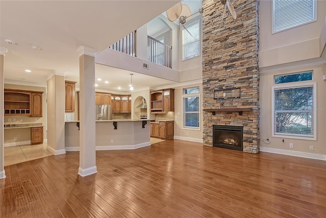 unfurnished living room with crown molding, built in desk, hardwood / wood-style flooring, a fireplace, and a high ceiling