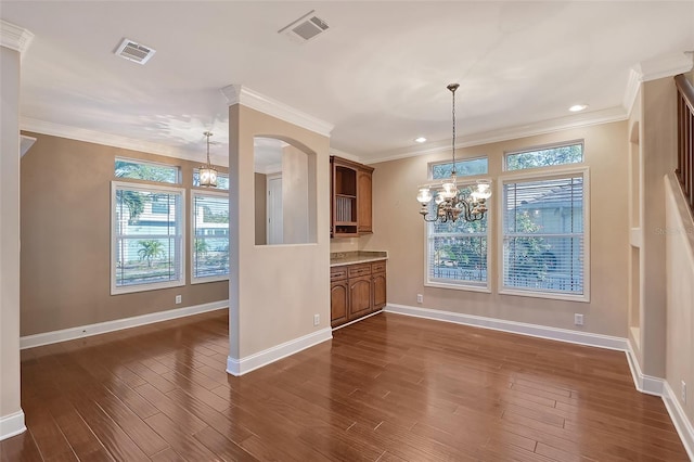 unfurnished dining area with dark hardwood / wood-style floors, crown molding, and a chandelier