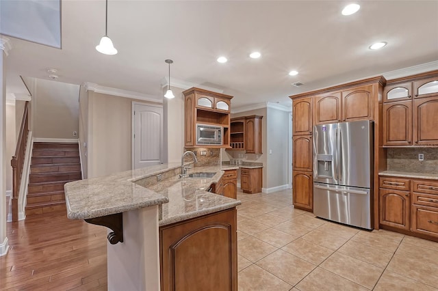 kitchen with sink, ornamental molding, decorative light fixtures, kitchen peninsula, and stainless steel appliances