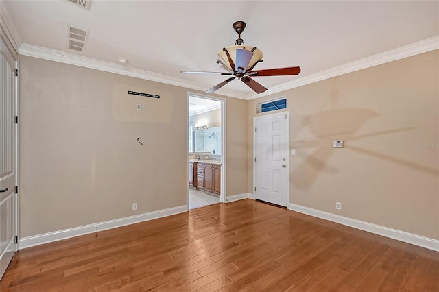 empty room featuring crown molding, ceiling fan, and wood-type flooring