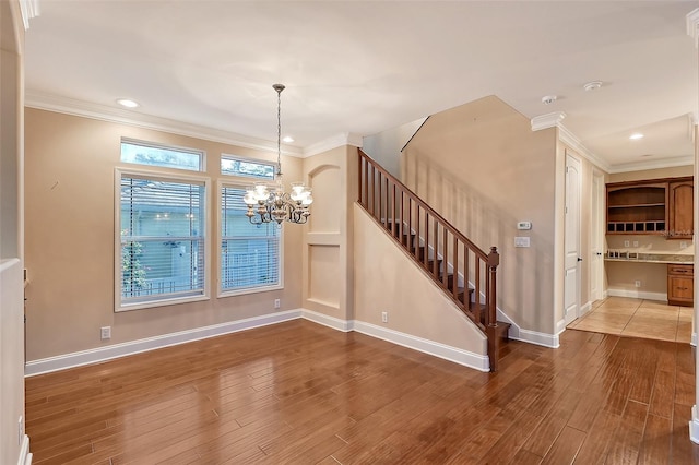 interior space featuring an inviting chandelier, ornamental molding, and hardwood / wood-style flooring