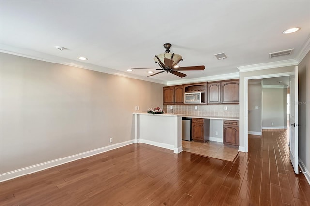 kitchen featuring backsplash, dark hardwood / wood-style flooring, ornamental molding, and stainless steel appliances