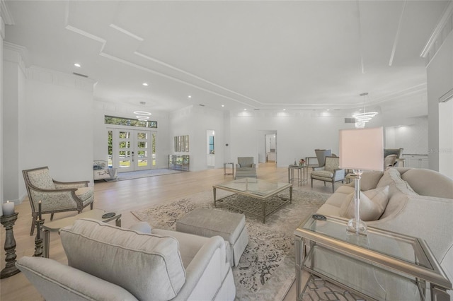 living room featuring french doors, ornamental molding, and light hardwood / wood-style flooring