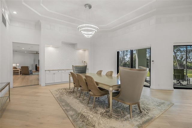 dining space with light hardwood / wood-style flooring, a towering ceiling, and a healthy amount of sunlight