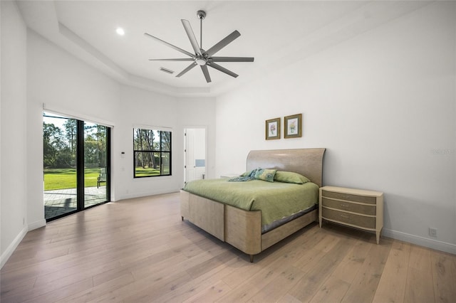 bedroom featuring ceiling fan, light hardwood / wood-style floors, a towering ceiling, and access to outside