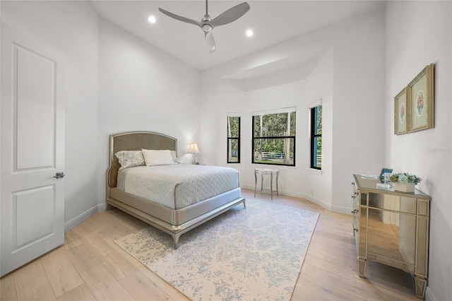 bedroom with ceiling fan, a high ceiling, and light wood-type flooring