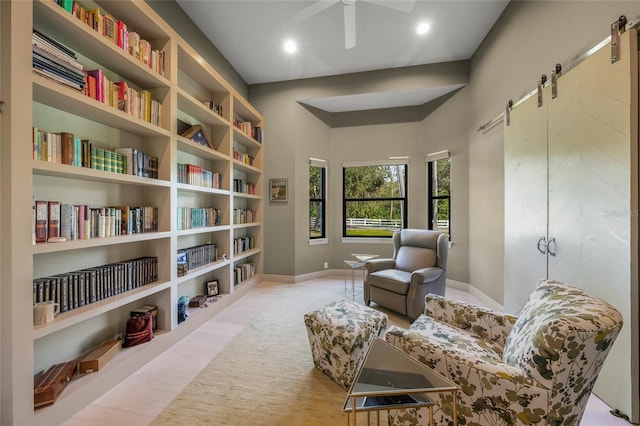 living area featuring a barn door and ceiling fan