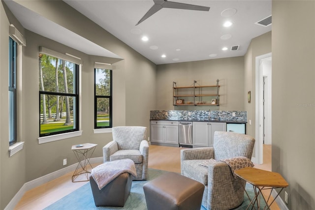 living area featuring ceiling fan and sink