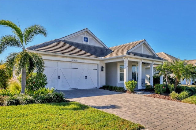8089 Sandstar Way, Sarasota, FL 34240 - ranch-style home featuring an attached garage, decorative driveway, a tiled roof, and stucco siding