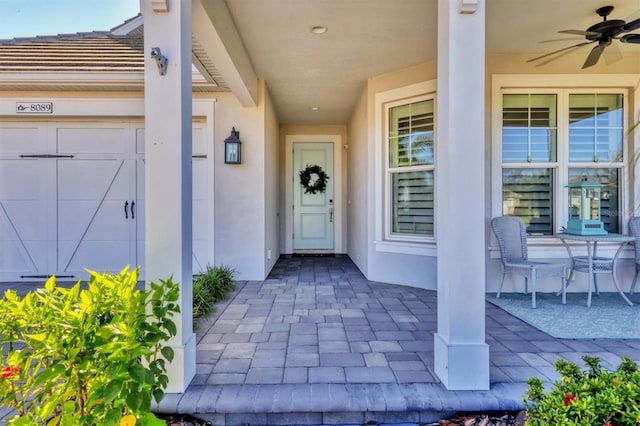 8089 Sandstar Way, Sarasota, FL 34240 - doorway to property featuring stucco siding, a ceiling fan, and a garage