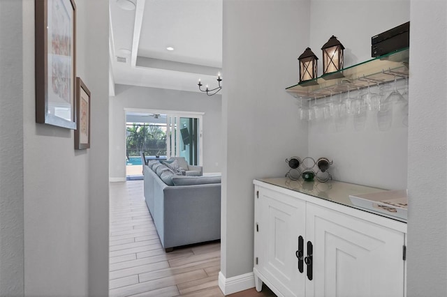 interior space with white cabinets, light wood-type flooring, and a notable chandelier