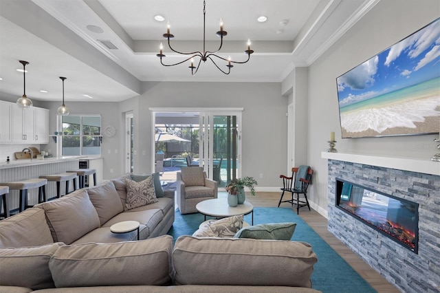 8089 Sandstar Way, Sarasota, FL 34240 - living area featuring wood finished floors, a raised ceiling, a stone fireplace, a chandelier, and recessed lighting
