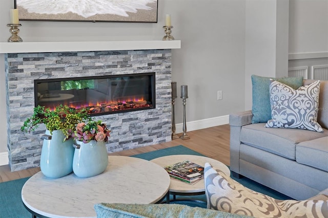 living room with a stone fireplace and hardwood / wood-style floors