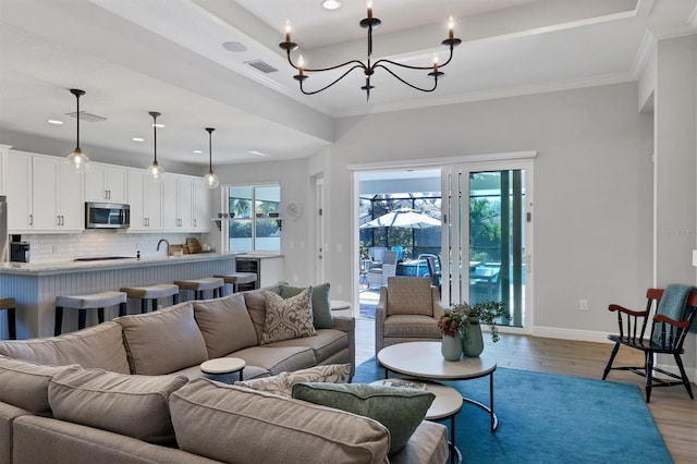 8089 Sandstar Way, Sarasota, FL 34240 - living area featuring wood finished floors, a chandelier, ornamental molding, and recessed lighting