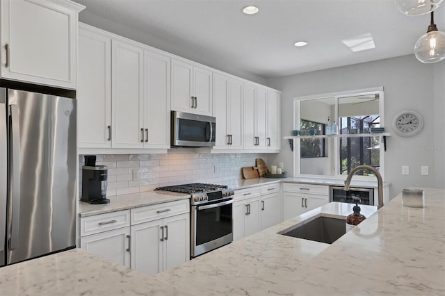 8089 Sandstar Way, Sarasota, FL 34240 - kitchen with stainless steel appliances, light stone countertops, backsplash, white cabinets, and recessed lighting