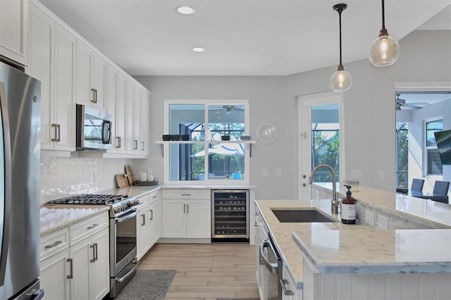 kitchen with white cabinets, plenty of natural light, stainless steel appliances, and beverage cooler