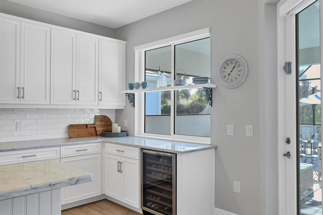 kitchen featuring light stone counters, white cabinetry, beverage cooler, and light hardwood / wood-style flooring