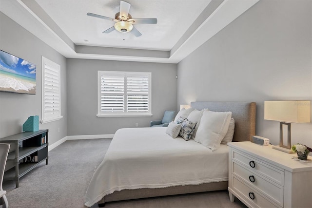 carpeted bedroom with a tray ceiling and ceiling fan