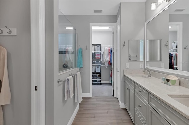 8089 Sandstar Way, Sarasota, FL 34240 - bathroom featuring a spacious closet, double vanity, wood finished floors, and a shower