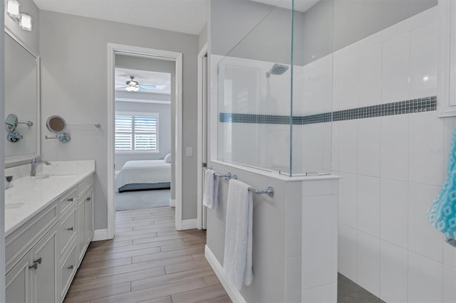 bathroom with hardwood / wood-style flooring, vanity, ceiling fan, and a tile shower