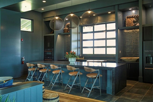 bar featuring dark hardwood / wood-style floors, oven, hanging light fixtures, and a wealth of natural light