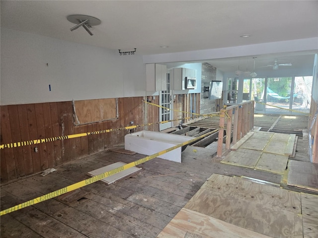 misc room featuring ceiling fan and wood walls