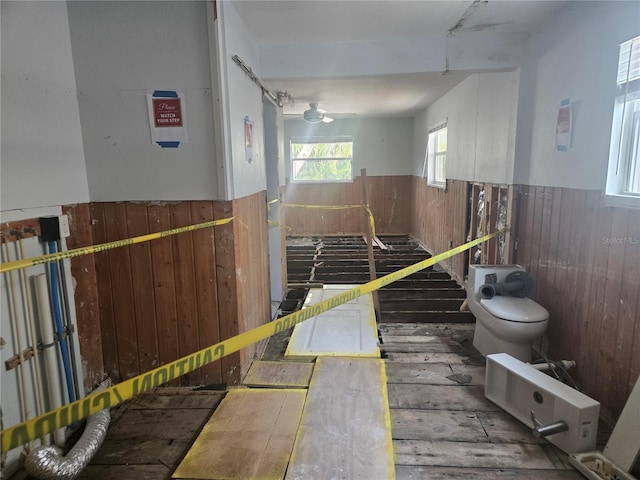 interior space featuring ceiling fan and wood walls