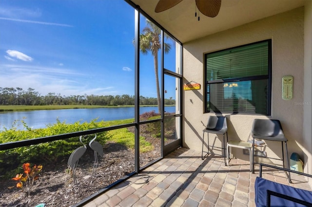 sunroom / solarium featuring a water view and ceiling fan