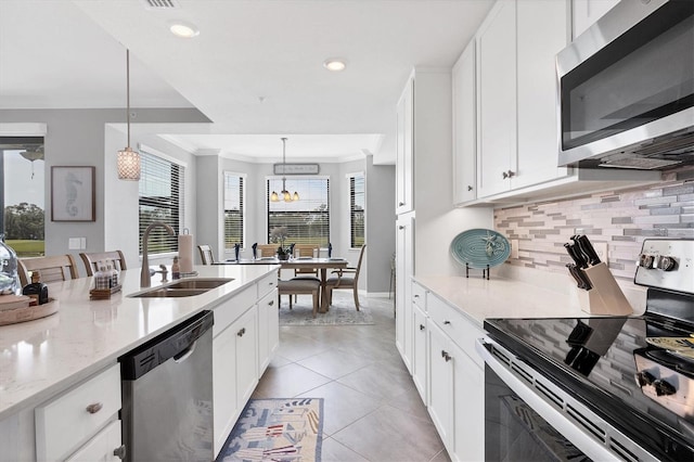 kitchen with white cabinets, sink, appliances with stainless steel finishes, decorative light fixtures, and light stone counters