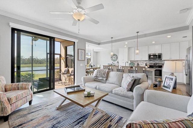 tiled living room with ceiling fan, a water view, and crown molding